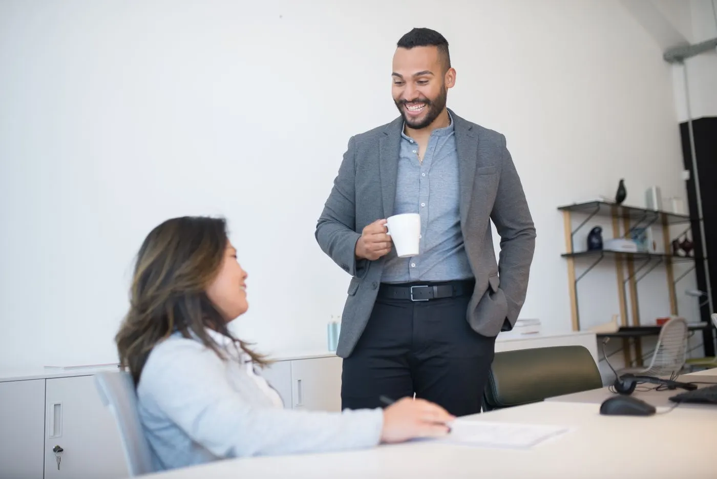 A colleague smiling and chatting with someone over coffee.